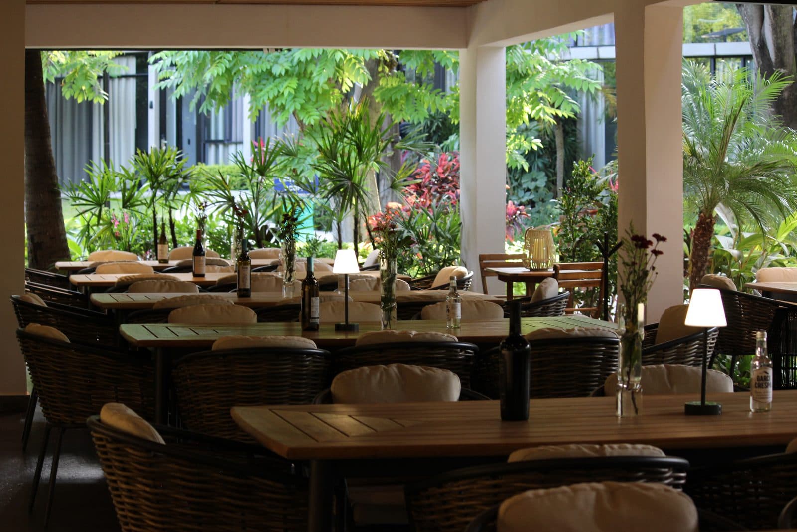 Terraza cubierta del restaurante Los Laureles, mesas de madera entre jardines